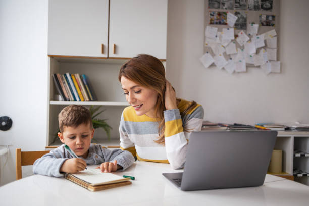 istock Young woman freelancer assisting son with homework at home 2159522657