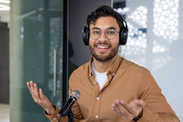 istock Young man hosting a podcast with headphones and microphone in modern studio 2159524271