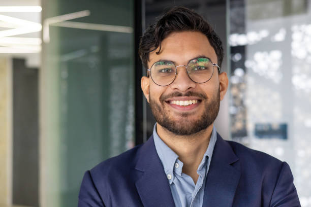 Confident young professional smiling in modern office environment Portrait of a confident young professional smiling indoors in a modern office. Perfect for business, corporate, and workplace concepts. office buddies stock pictures, royalty-free photos & images