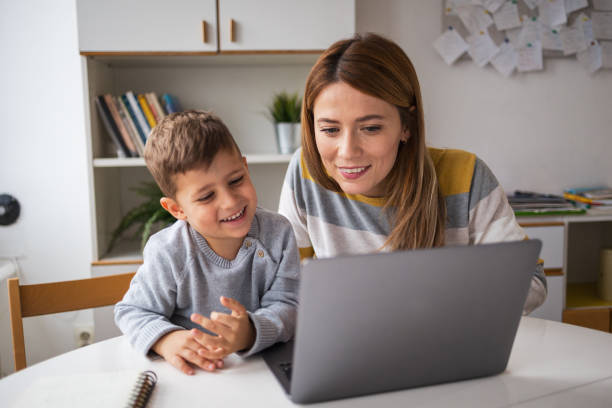 Happy mother and son using laptop during online class at home
