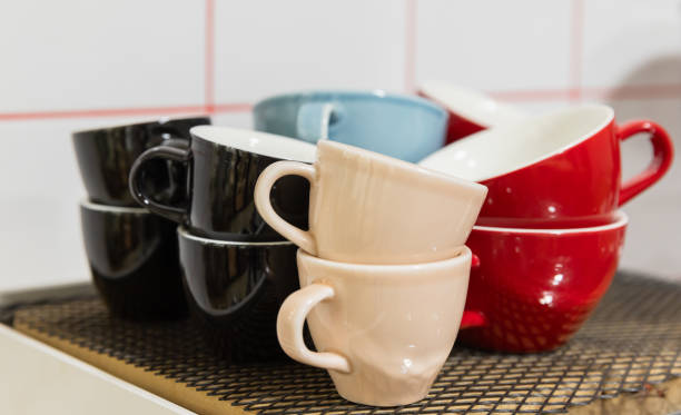istock Set of bright ceramic cups stand in front of white wall 2159526428