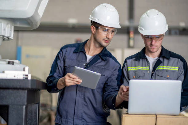 istock Two engineers stand in a robotic arm workshop, engaging in a detailed discussion while updating the software to control a robot. They are surrounded by advanced equipment, showcasing their expertise in automation and robotics. 2159527237