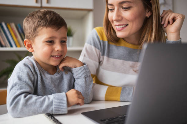 istock Happy mother watching son using laptop at table in apartment 2159527316