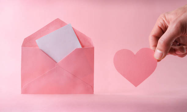 Red envelope with blank paper, red ribbon, hearts on silk. Happy Valentines Day, wedding concept.