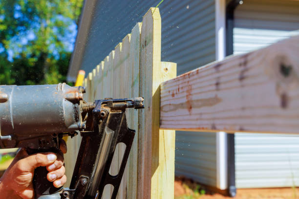 istock Using an air pneumatic gun, worker nails a wooden plank fence 2159537380