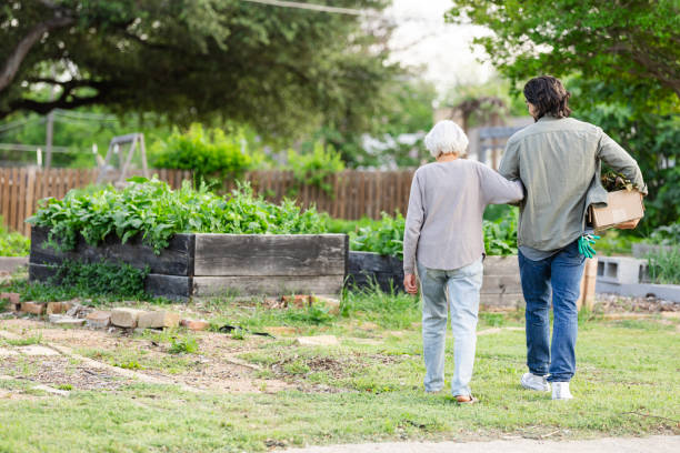 istock Unrecognizable son walks arm-in-arm around garden with unrecognizable senior mom 2159537605