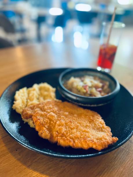 istock Breaded fish fillet served with mashed potatoes and tomato sauce on wooden table 2159539284