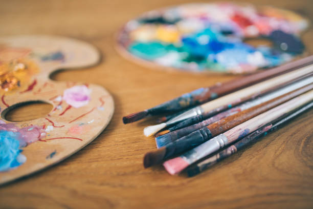 Artist's palette and paintbrushes on wooden background.