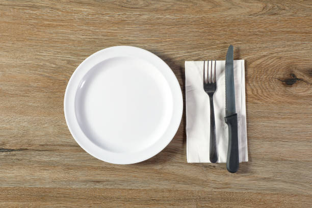 istock One empty ceramic plate with fork and knife on wooden table 2159542711