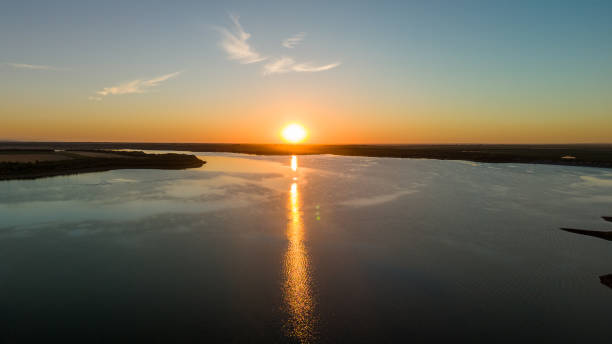 istock Golden sunset reflecting over a wide lake surrounded by fields 2159546364