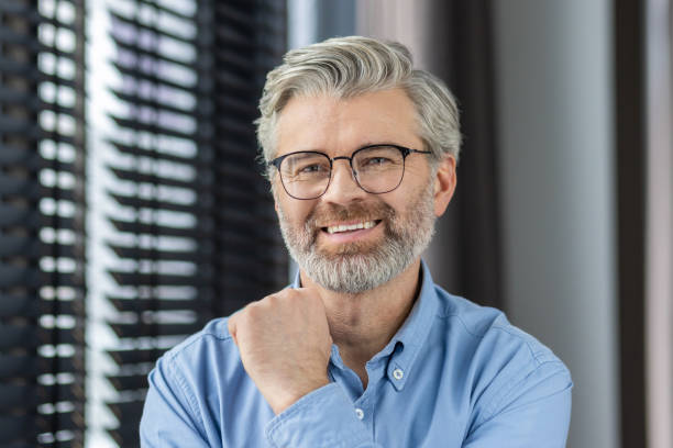 istock Confident and happy elderly man with grey hair and glasses smiling in a modern office setting 2159548491