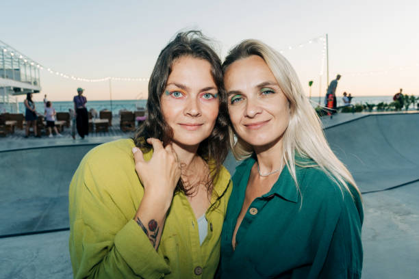istock Two beautiful women with multi-colored makeup on their eyes look at the camera while standing on the street. 2159549361