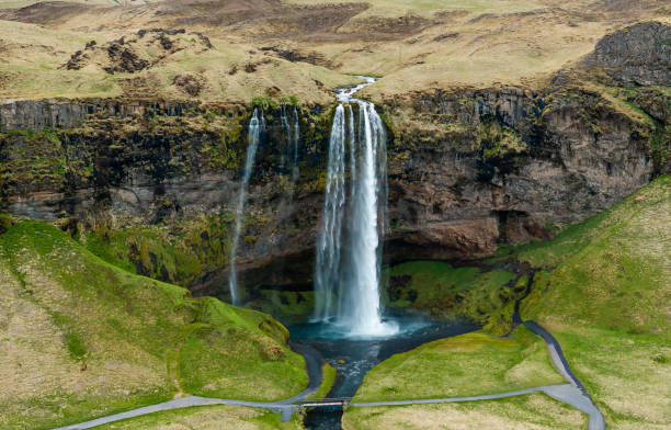 istock Aerial view of Seljalandsfoss waterfall in Iceland, cascading over cliffs into a serene pool surrounded by lush green landscape. 2159551280