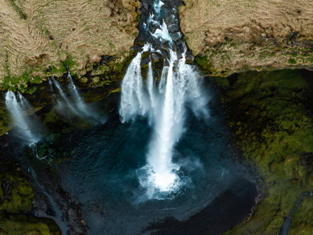 istock Aerial view of Seljalandsfoss waterfall in Iceland, cascading over cliffs into a serene pool surrounded by lush green landscape. 2159551301