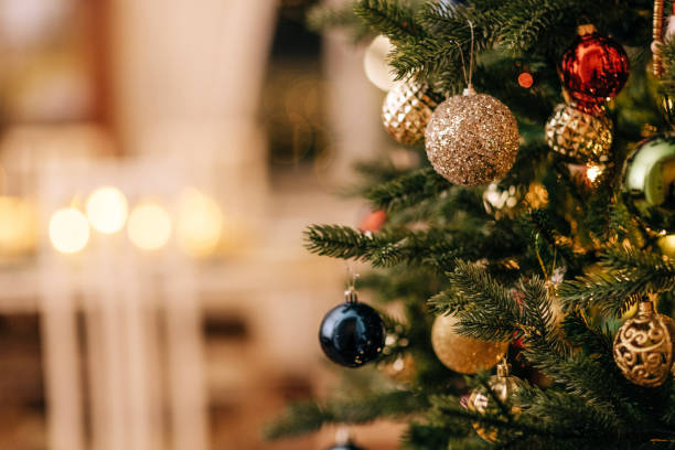 A close-up of a decorated Christmas tree with vintage glass toys. A close-up of a decorated Christmas tree with vintage glass toys. Stylish rich interior with fireplace and lighted candles. New year decorations. Copy space. images of decorated christmas trees stock pictures, royalty-free photos & images