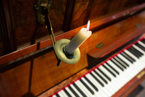 A beautifully arranged candelabra with flickering candles next to a grand piano, creating a cozy and inviting atmosphere for music