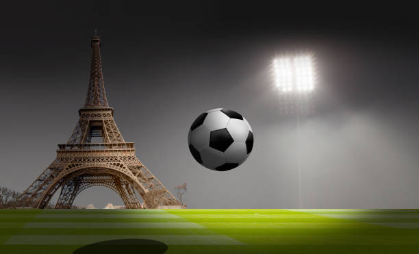 Soccer ball  is under the projector with green field Eiffel tower in the background
