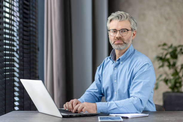 istock Mature businessman working on laptop in modern office setting 2159554633