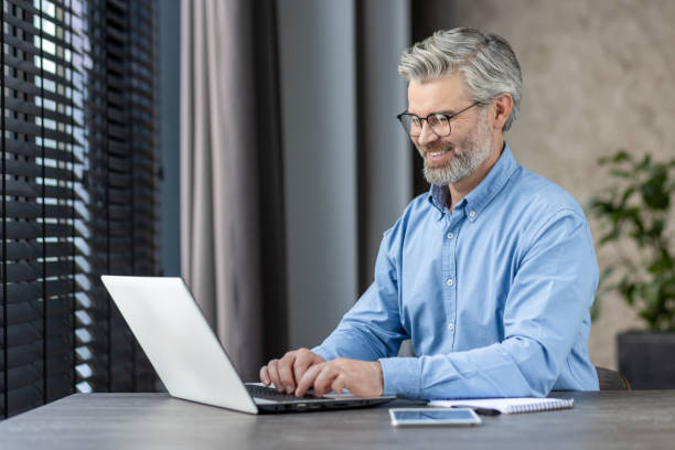 istock Smiling mature businessman working on laptop in office 2159555208