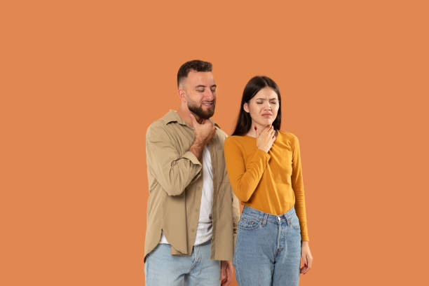 istock Young Couple Expresses Discomfort While Holding Necks Against Orange Background 2159555795
