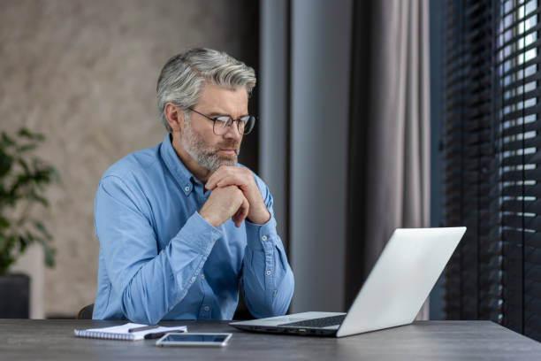 istock Focused mature man working on laptop in modern office environment 2159556836