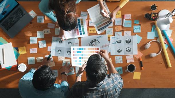 istock Top view of skilled designer holding logo while discussing with team. Symposium. 2159557647