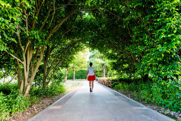 Woman walking through green natural tunnel.