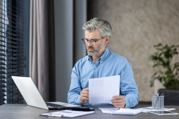 istock Senior professional reviewing documents in a modern office environment with focus and determination 2159561746