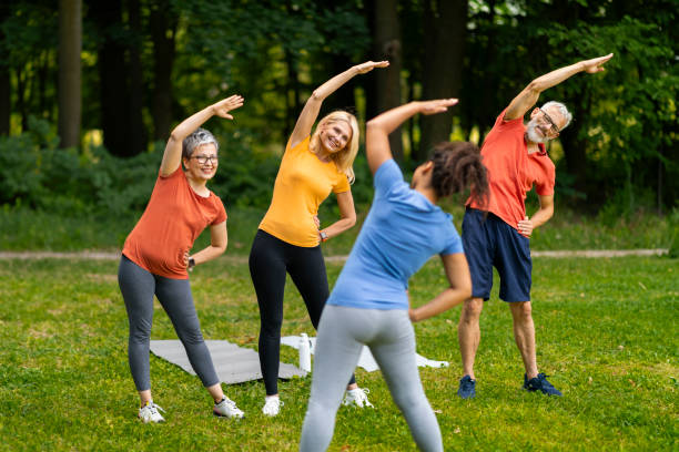 istock Group of seniors following yoga stretch routine outdoors, led by younger instructor 2159563467