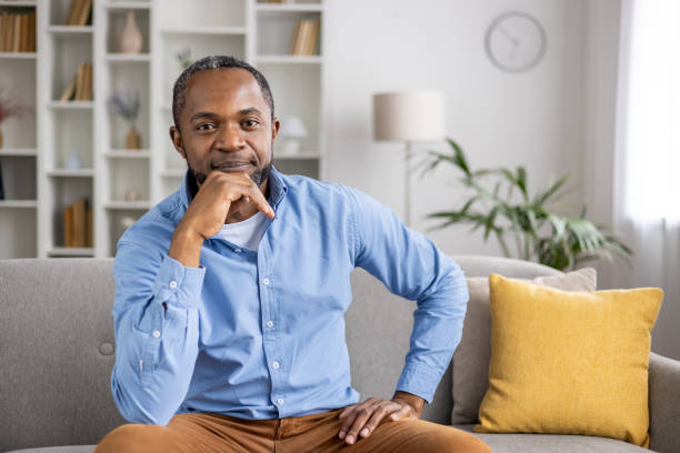 istock Confident man sitting on a couch in a modern home interior, smiling and relaxed 2159564604