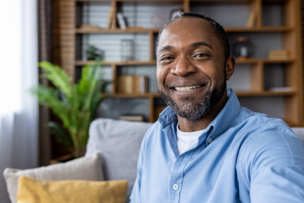istock Happy man smiling while sitting on a couch at home 2159565269