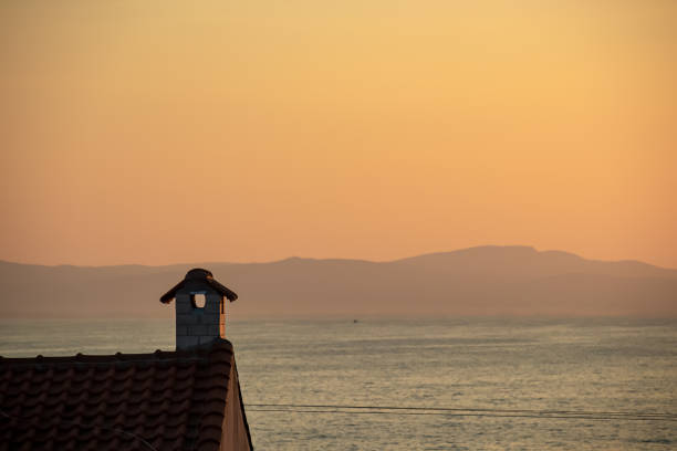 Panoramic view on chimney of house overlooking the Mediterranean sea during sunrise. Early morning vibes. Vacation in Greece