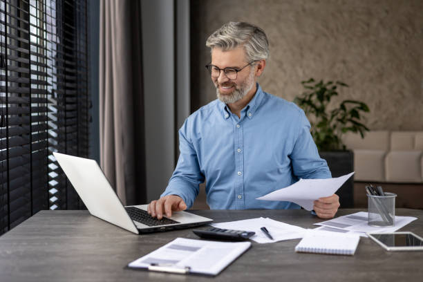 istock A senior businessman is working on his laptop in a modern office, handling documents 2159567258