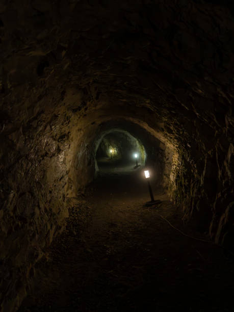 istock Long underground passage carved into rock and illuminated by lights 2159568014