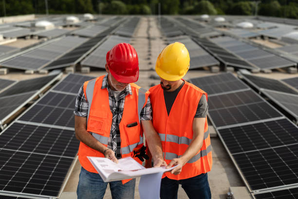 istock Technicians in reflective vests checking solar power plant installed on building roof 2159568134