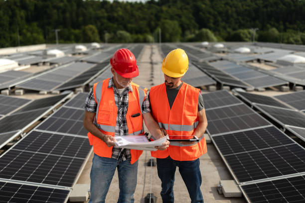istock Technicians in reflective vests checking solar power plant installed on building roof 2159568140