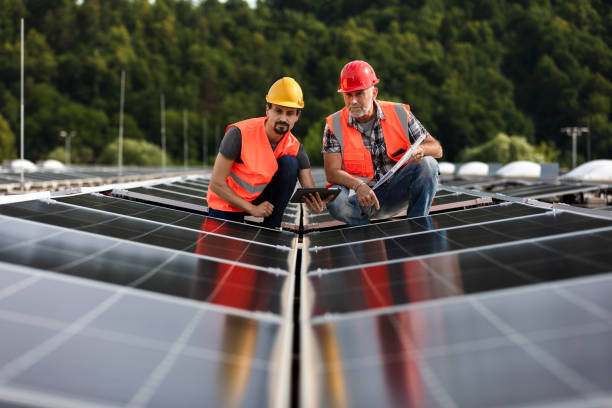 istock Technicians in reflective vests checking solar power plant installed on building roof 2159568142