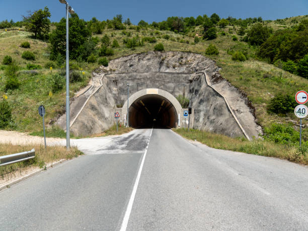 istock Empty asphalt road leading to a tunnel in mountain area 2159568411