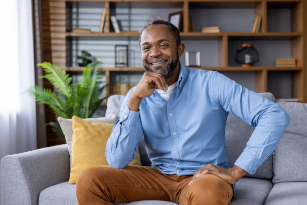 istock Smiling man sitting on sofa in modern living room with natural light 2159569242