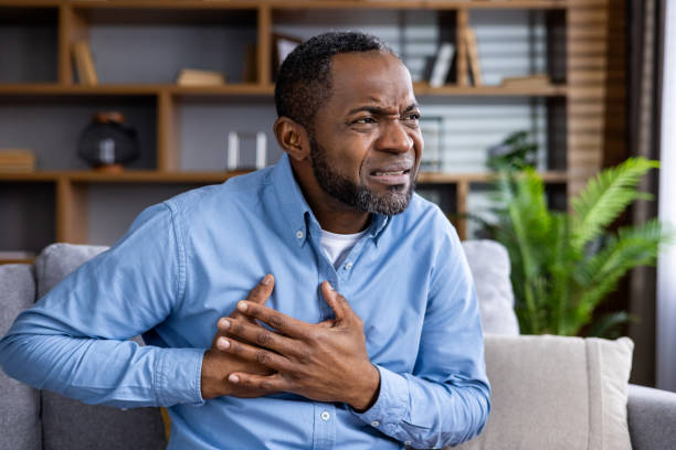 istock Man experiencing chest pain sitting on a sofa in a home setting 2159569851