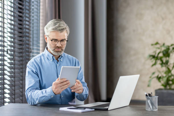 istock Businessman using tablet and laptop at desk in modern office 2159569905