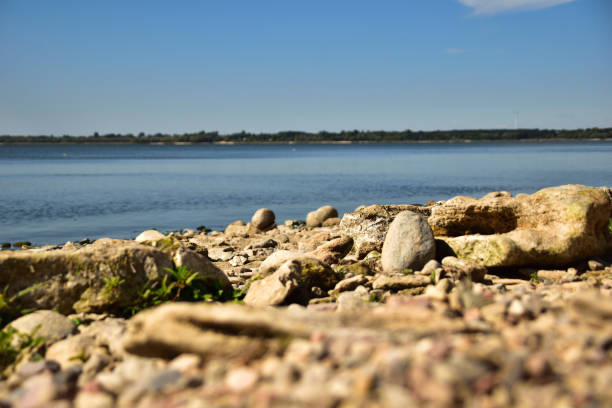 The stony bank of the Warta River with blue sky.