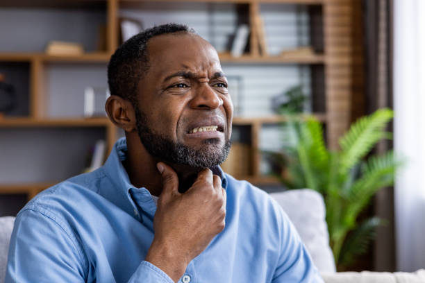 istock Man experiencing throat pain at home, touching his neck 2159570864