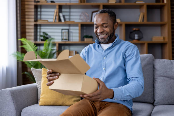 Smiling man unboxing a package while sitting on a couch at home