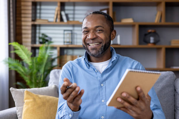 istock Smiling man holding a notebook and having a video call at home 2159571274
