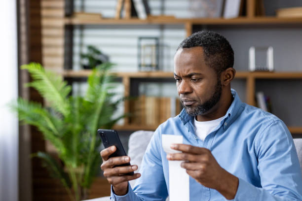 istock Serious man pays utility bill using app on phone at home 2159573080