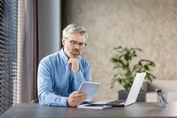 Senior businessman working on tablet at home office desk