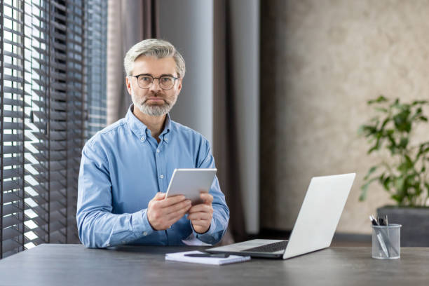 istock Mature businessman using a digital tablet in modern office setting 2159574694
