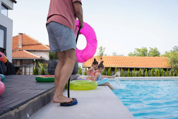istock Young father preparing pool inflatables, ensuring his daughters enjoy a swimming pool 2159578985