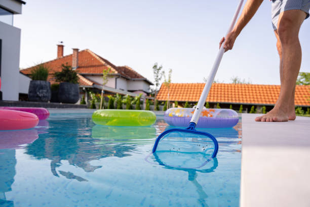 istock Young man cleaning his swimming pool with a net in the backyard 2159578994